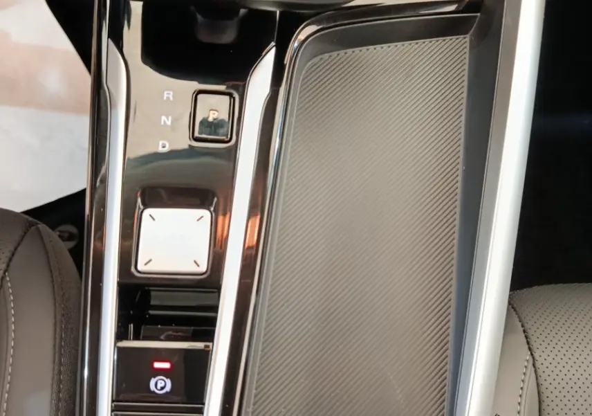 Gros plan sur la console centrale noire et grise du MG ZS Hybrid+ Luxury avec levier de vitesses automatique et bouton parking.