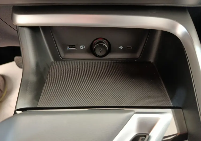 Gros plan sur la console centrale noire du MG ZS Hybrid+ Luxury avec prises USB, prise 12V et surface texturée antidérapante.