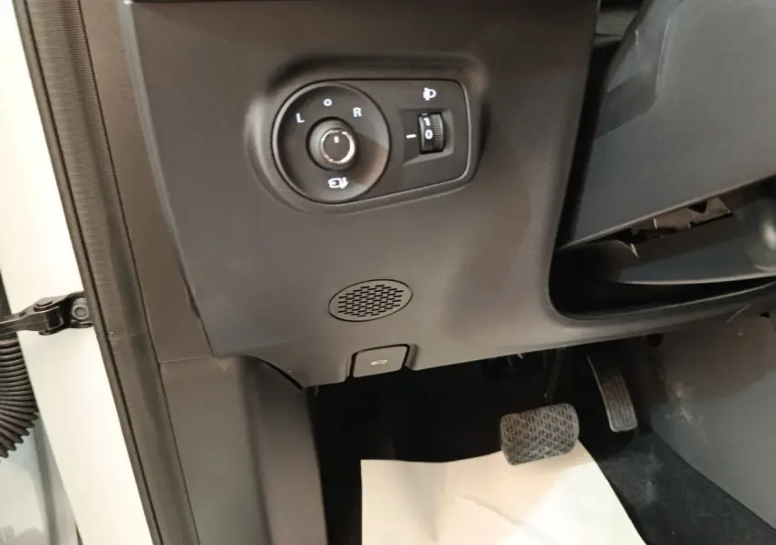 Détail intérieur côté gauche avec commande réglage rétroviseurs et pédale d'accélérateur d'un MG ZS blanc.