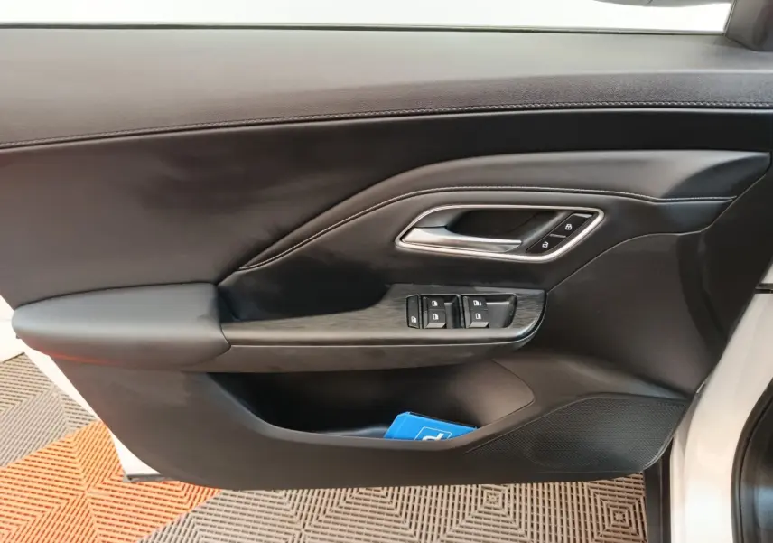 Gros plan sur la porte avant droite noire du MG ZS blanc, avec commandes de vitres et poignée argentée.