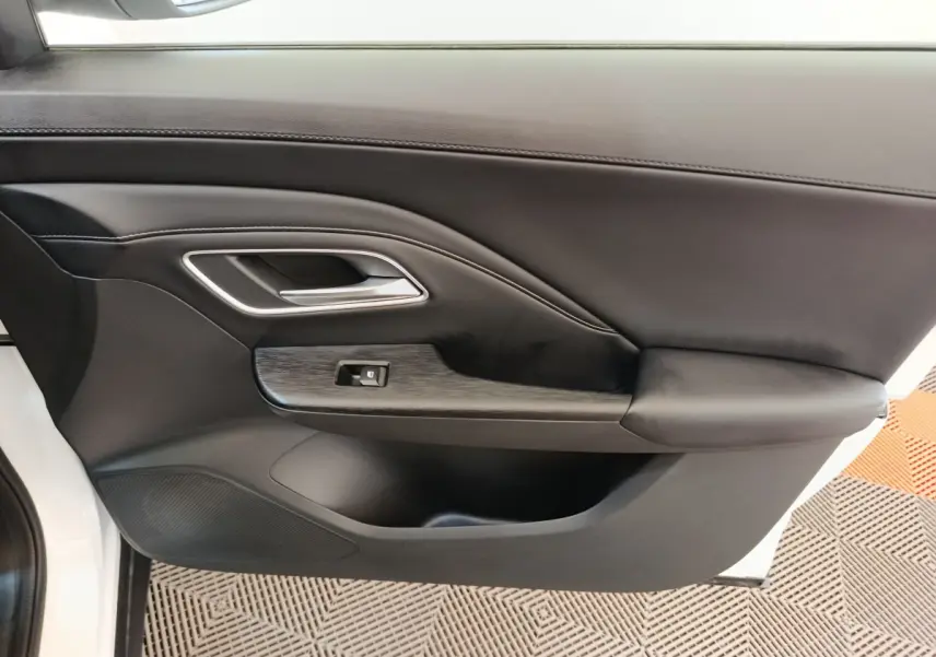 Gros plan sur la porte intérieure côté conducteur du MG ZS blanc, avec accoudoir et commande de fenêtre.