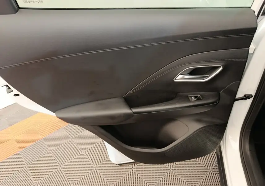 Vue côté gauche de la porte avant blanche du MG ZS 1.5L Hybrid+ Luxury avec garniture intérieure noire et poignée argentée.