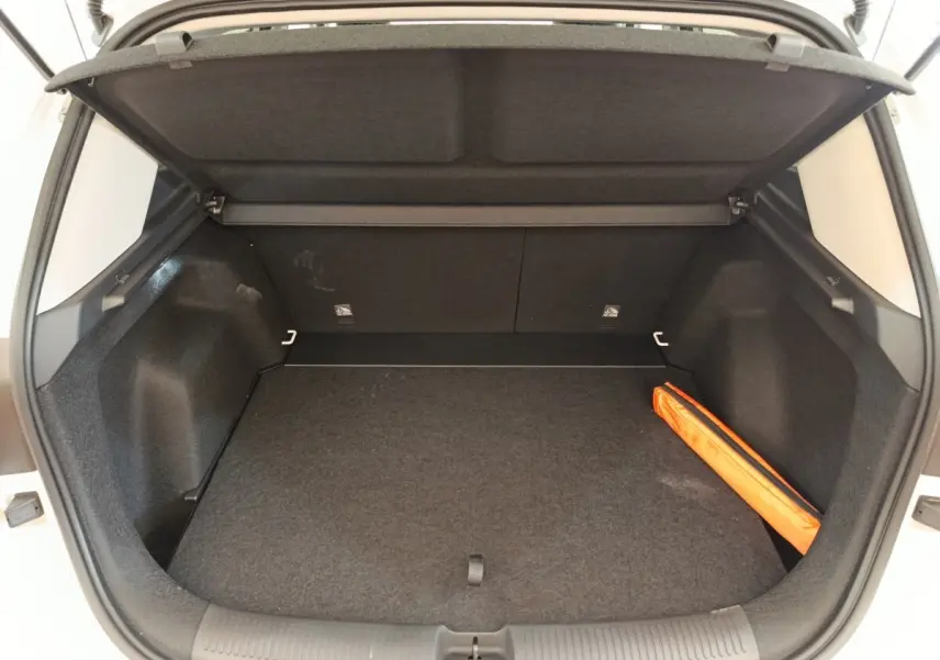 Coffre ouvert du MG ZS blanc, vue arrière, montrant un espace de rangement avec un triangle de sécurité orange.