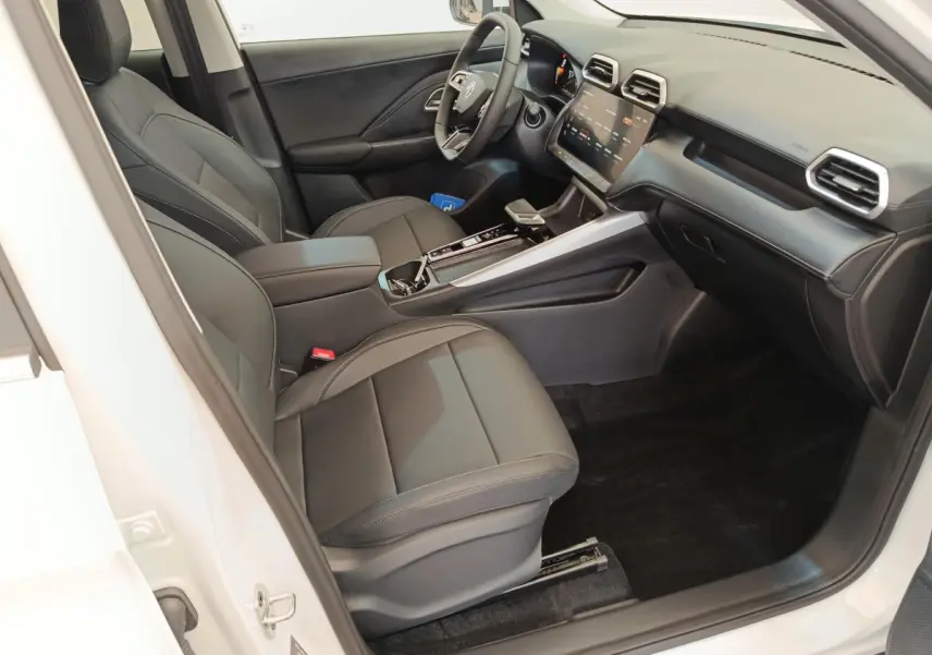 Vue intérieure côté conducteur du MG ZS blanc, mettant en valeur les sièges noirs et l'écran tactile central.