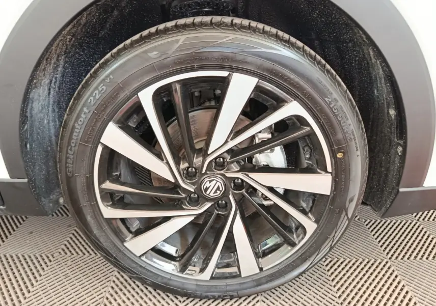 Gros plan sur la jante alliage bicolore noire et argent du MG ZS blanc, roue avant droite visible.