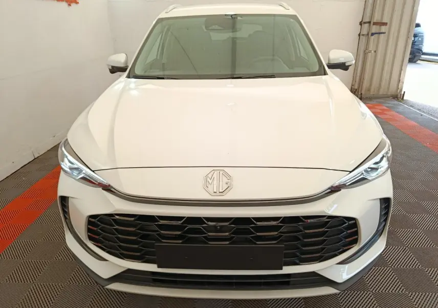 Vue avant d'un MG ZS blanc 2026 avec calandre noire et phares LED fins dans un garage.