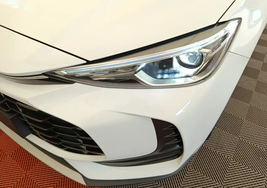 Gros plan sur le phare avant droit blanc du MG ZS 1.5L Hybrid+ Luxury avec calandre noire et détails modernes.