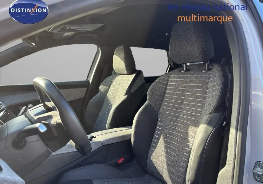 Vue intérieure côté conducteur du Peugeot 5008 blanc Okenite 2025, mettant en valeur les sièges tissu noir et cuir.
