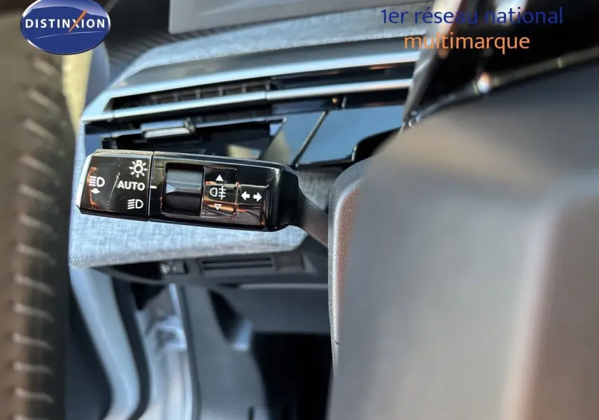 Gros plan sur la commande des feux et clignotants du Peugeot 5008 hybride 2025, intérieur gris et noir.