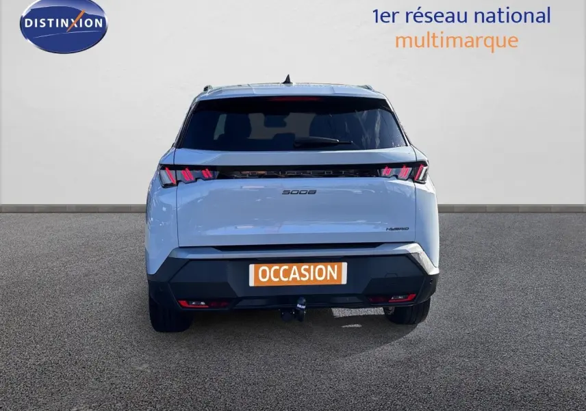 Vue arrière d’un Peugeot 5008 blanc Okenite hybride 2025 avec feux LED distinctifs et attelage visible.