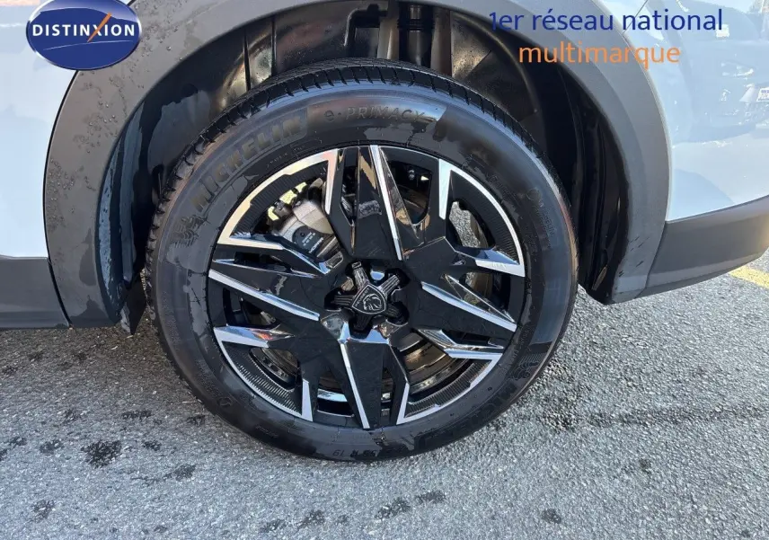 Gros plan sur la roue avant droite du Peugeot 5008 blanc Okenite, mettant en valeur la jante noire et argentée.