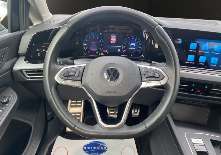 Vue intérieure centrée sur le volant et tableau de bord numérique de la Volkswagen Golf VIII noire de 2022.