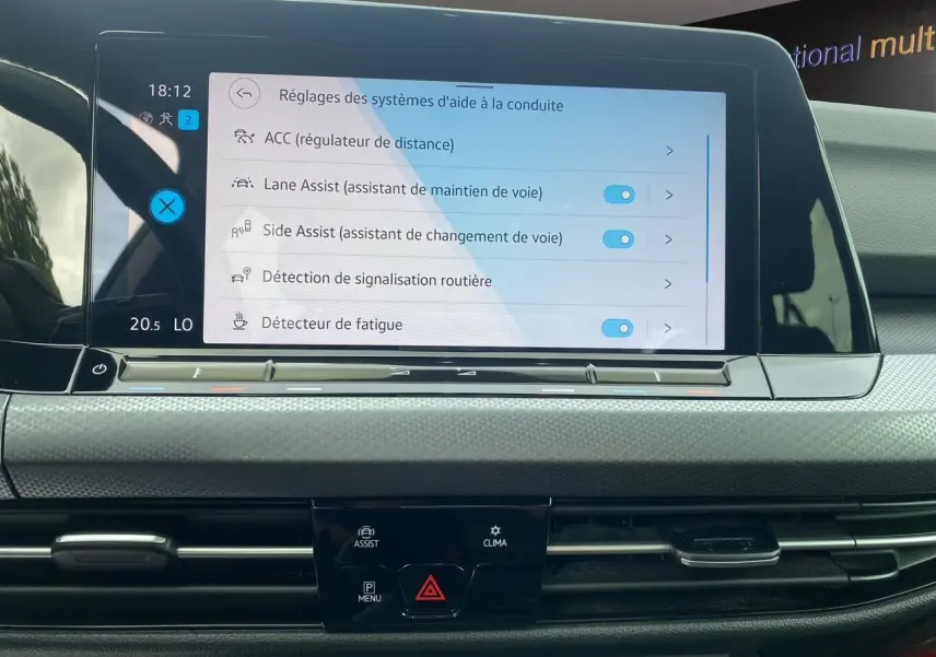 Écran tactile central de la Volkswagen Golf VIII noire de 2022 montrant les réglages d'aides à la conduite.