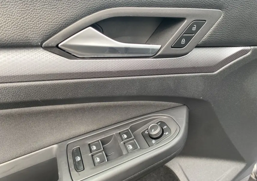 Détail de la porte côté conducteur d'une Volkswagen Golf VIII noire, avec commandes des vitres et serrure intégrée.