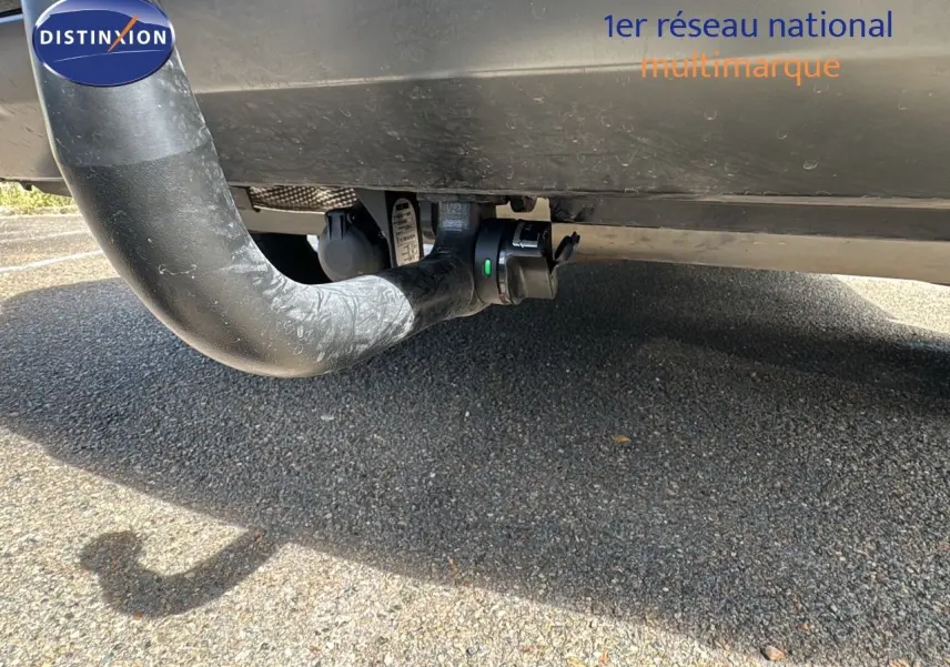 Gros plan sous le pare-chocs arrière d'une Renault Rafale blanc satin avec attelage visible sur fond de bitume.