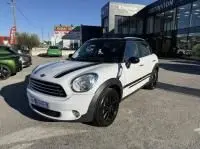 MINI Countryman Cooper 122 Pack Chili blanc vue 3/4 avant droit, avec jantes noires et toit noir, stationnée en extérieur.