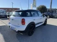 Vue 3/4 arrière droite d'une MINI Countryman Cooper 122 Pack Chili blanche avec jantes noires, stationnée en extérieur.