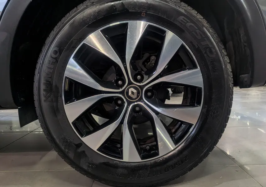Gros plan sur la jante alliage biton avec logo Renault au centre, montée sur un pneu Kumho d’un Renault Arkana gris métal.