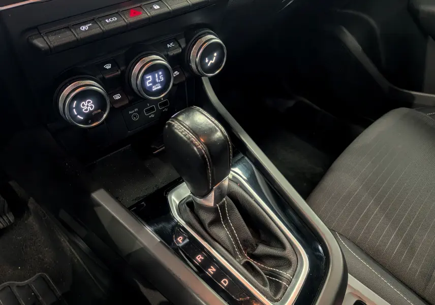 Gros plan sur la console centrale et levier de vitesses automatique d’un Renault Arkana gris métal, intérieur tissu noir.