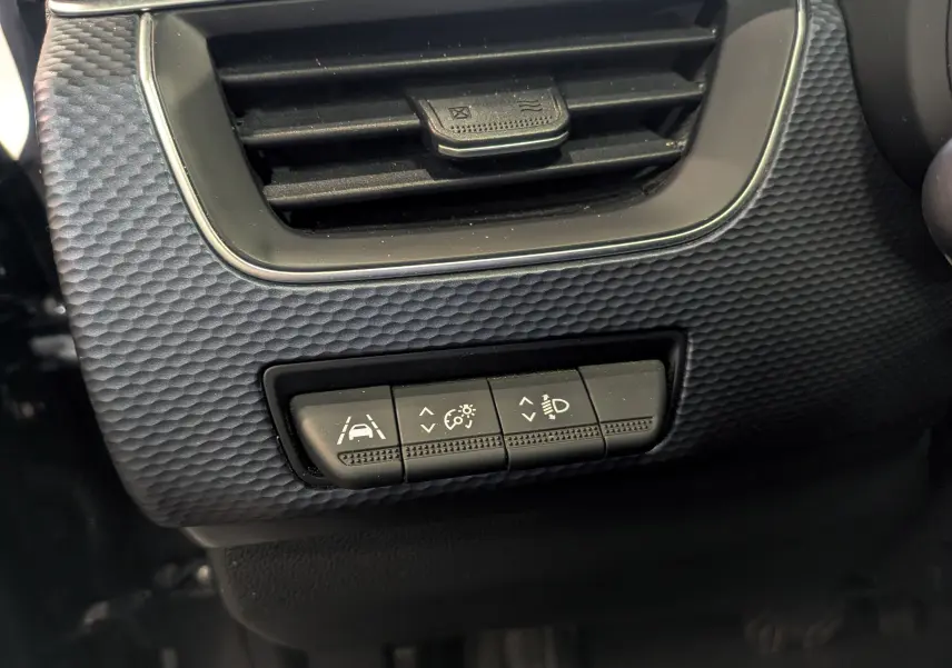 Détail intérieur du tableau de bord du Renault Arkana TCe 140 Business 2022, avec commandes d'assistance à la conduite sous la sortie d'air.