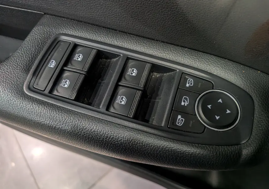 Gros plan sur les commandes de lève-vitres et réglages des rétroviseurs côté conducteur d’un Renault Arkana gris métal.