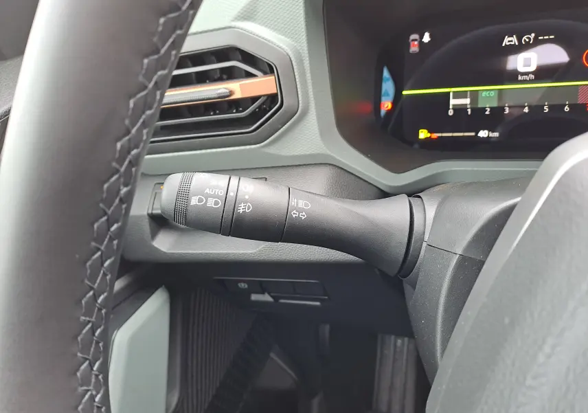 Gros plan sur la manette de clignotant à gauche du volant dans l’habitacle gris du Dacia Bigster noir nacré 2025.