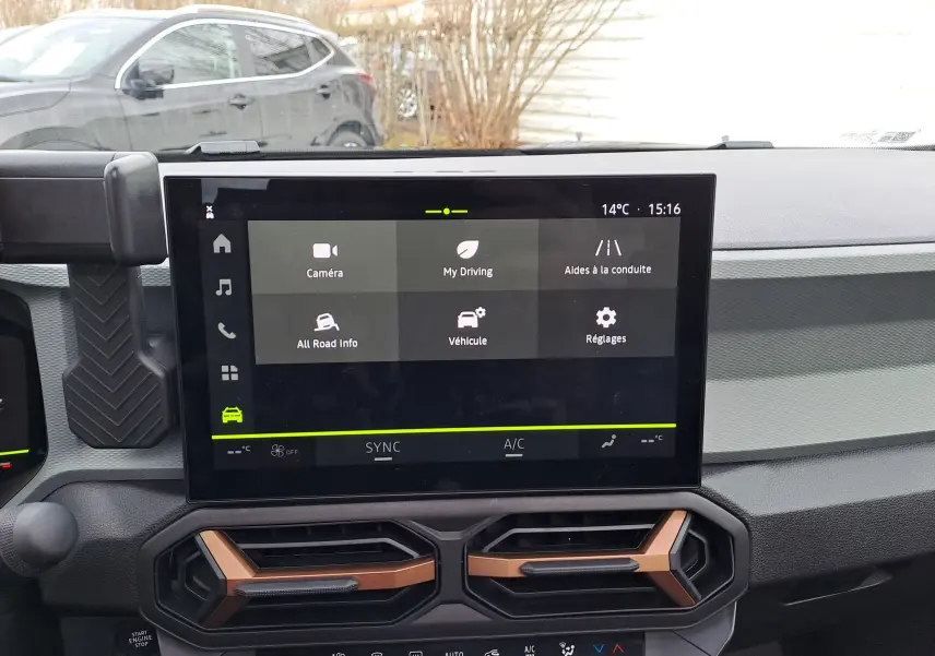 Vue intérieure centrée sur l’écran tactile du tableau de bord du Dacia Bigster noir nacré, avec aérateurs bronze visibles.