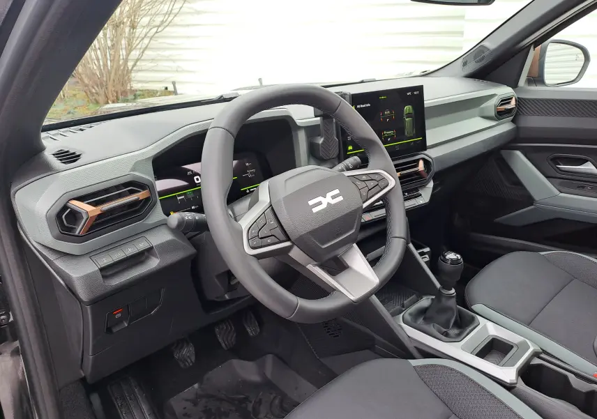 Vue intérieure côté conducteur du Dacia Bigster noir nacré 2025, tableau de bord moderne avec écran tactile et volant multifonction.