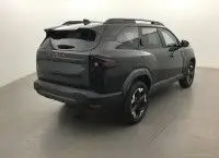 Gros plan sur la roue avant gauche du Dacia Bigster noir nacré, mettant en valeur la jante bi-ton au design géométrique.