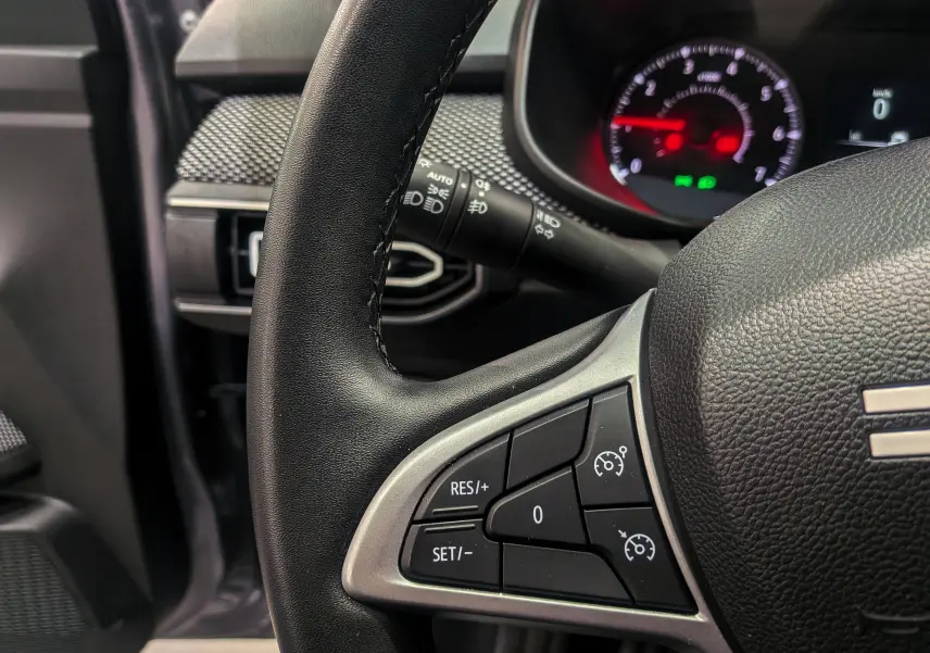 Gros plan sur le volant noir de la Dacia Sandero TCe 90 CH Journey 2025, avec commandes de régulateur de vitesse visibles.