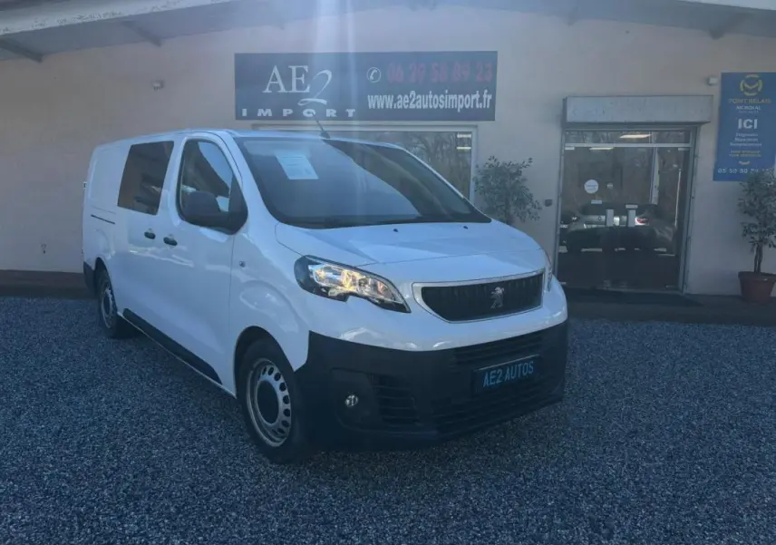Peugeot Expert Fourgon blanc vu en 3/4 avant droit, avec calandre noire et jantes tôles, stationné devant un garage.