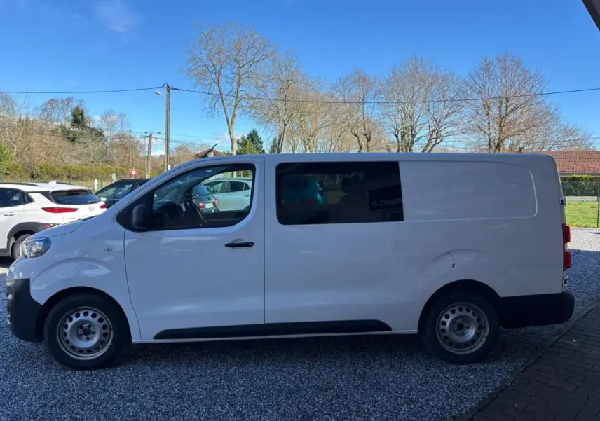 Peugeot Expert Fourgon blanc vu de profil côté gauche, avec fenêtre teintée sur la porte coulissante arrière.
