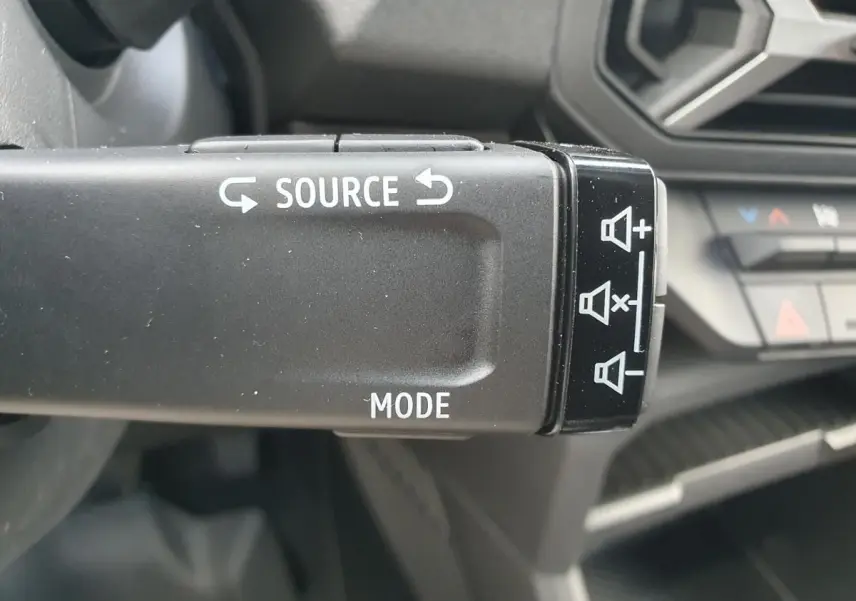 Gros plan sur la commande au volant du Dacia Duster 2026 gris schiste, avec boutons source et mode visibles.