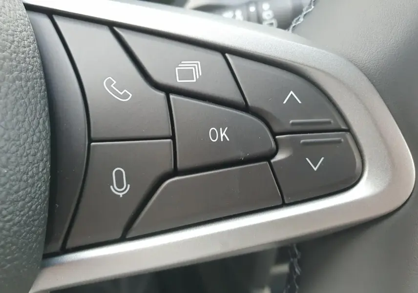 Gros plan sur les boutons de commande au volant du Dacia Duster 2026, finition gris schiste, avec commandes vocales et navigation.