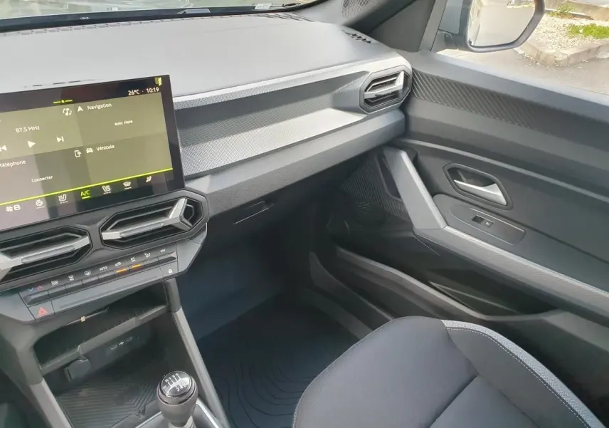 Vue intérieure côté passager du tableau de bord et console centrale du Dacia Duster 2026 avec écran tactile et boîte manuelle.