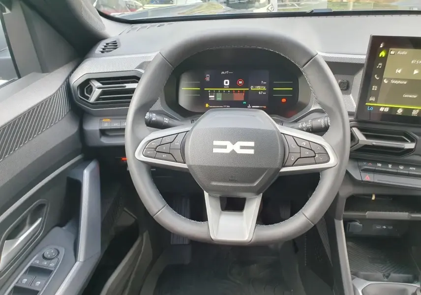 Vue intérieure centrée sur le volant multifonction du Dacia Duster 2026 avec tableau de bord numérique et écran tactile.