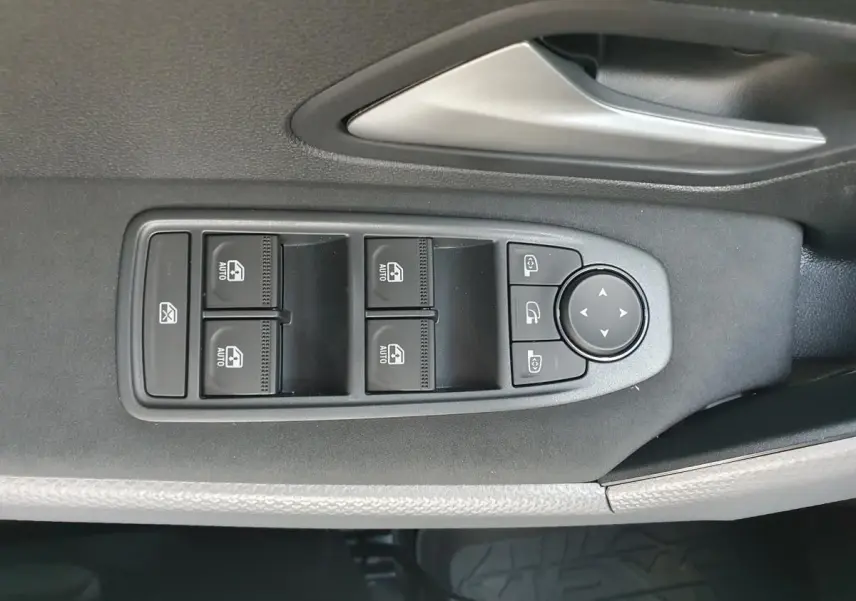 Gros plan sur les commandes de lève-vitres et rétroviseurs côté conducteur du Dacia Duster gris schiste 2026.
