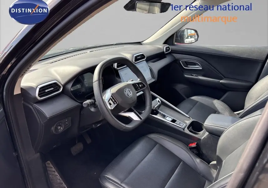 Intérieur du MG ZS 1.5L Hybrid+ 2025 en Pebble Black, vue côté conducteur montrant tableau de bord et sièges cuir noirs.