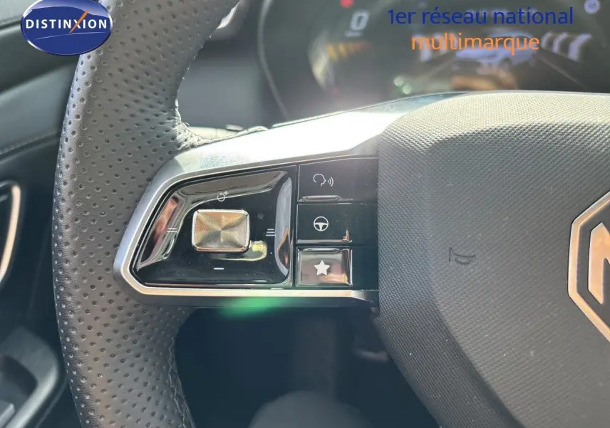 Gros plan sur le volant perforé noir du MG Motor ZS 2025 avec commandes intégrées et logo MG visible.