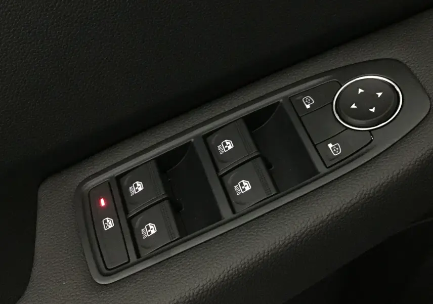 Gros plan sur les commandes de lève-vitres et rétroviseurs électriques côté conducteur d'une Renault Clio V gris schiste.