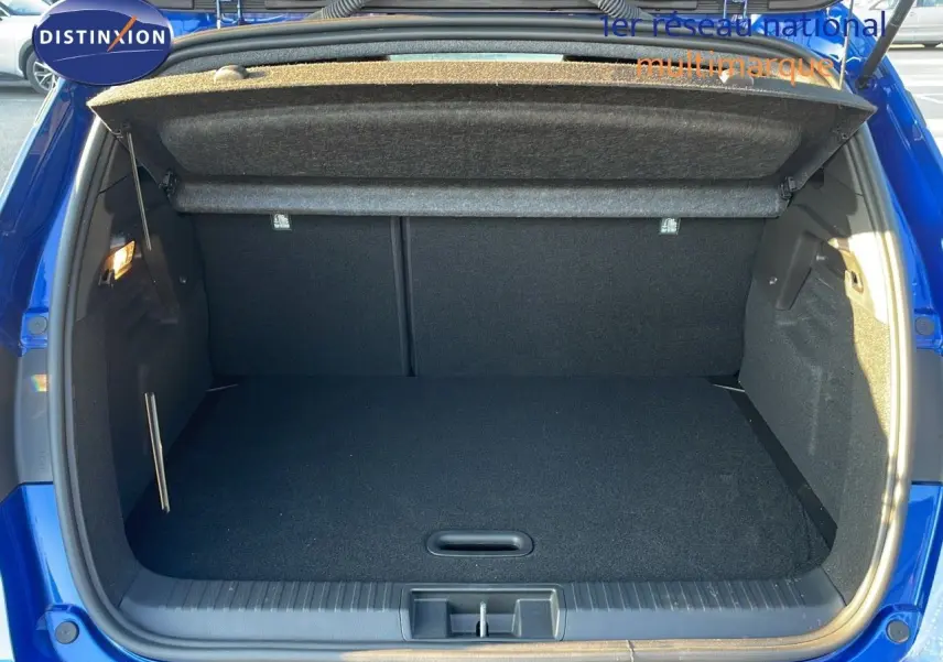Coffre ouvert d'un Renault Captur E-Tech hybride 2025 bleu Iron Metal, montrant l'espace de chargement vide et la moquette noire.