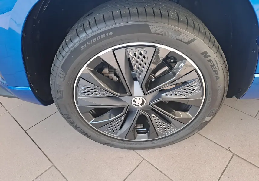 Gros plan sur la roue avant droite du SKODA KAROQ Bleu RS avec jante alliage noire et grise au design moderne.