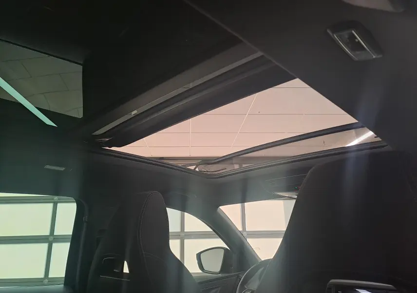 Vue intérieure du toit panoramique ouvrant électrique du Skoda Karoq Bleu RS 2025, avec sièges avant noirs visibles.