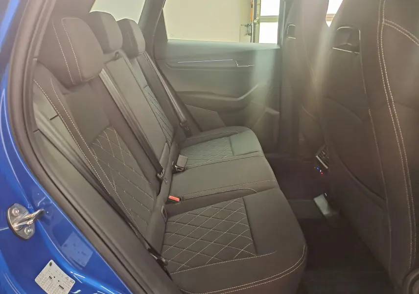 Vue intérieure côté gauche des sièges arrière en tissu noir avec surpiqûres contrastantes du Skoda Karoq Bleu RS 2025 Sportline.
