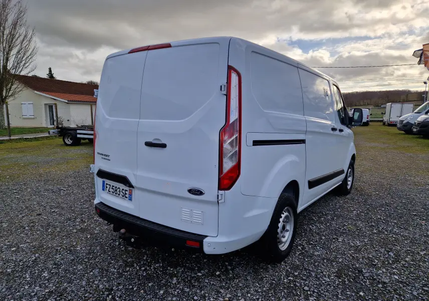 Vue 3/4 arrière droite d'un fourgon Ford Transit Custom blanc, avec portes arrière fermées et plaque d'immatriculation visible.
