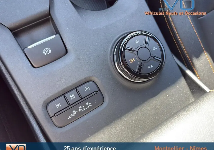 Gros plan sur la molette de modes de conduite et les boutons de contrôle du Ford Ranger Wildtrak noir, intérieur avec surpiqûres orange.