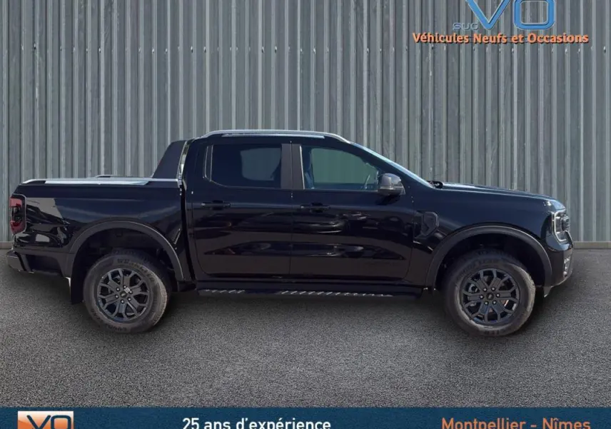 Vue latérale droite d'un Ford Ranger Wildtrak noir avec barres de toit, marchepieds et vitres surteintées.
