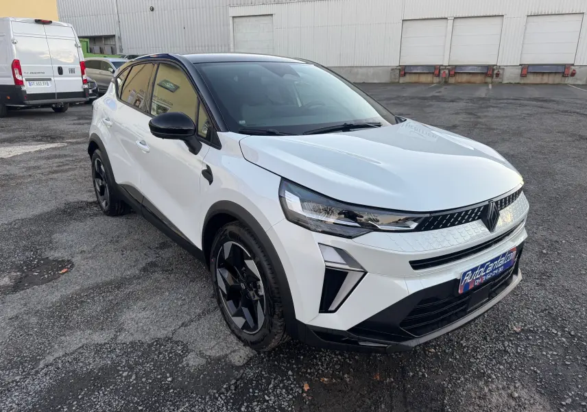 Vue 3/4 avant droite d’un Renault Captur 2025 blanc nacré avec toit noir et jantes noires sur parking.