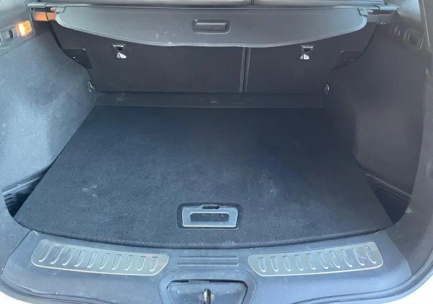 Vue arrière du coffre noir du Renault Koleos blanc 2019, avec cache-bagages et seuil de chargement visible.