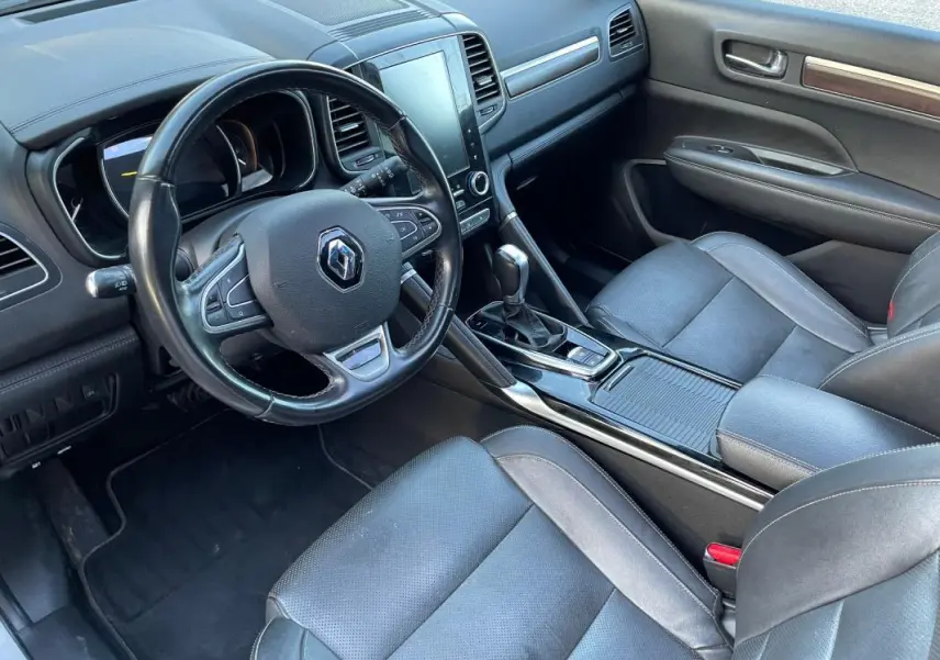 Vue intérieure côté conducteur du Renault Koleos 2019, tableau de bord noir avec écran tactile et accoudoir central.